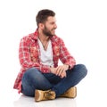 Man in lumberjack shirt sitting with legs crossed