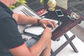 Man with luxury snakeskin python laptop case on a table outside the asian garden. Men fashion concept. Laptop bag. Royalty Free Stock Photo