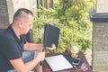 Man with luxury snakeskin python laptop case on a table outside the asian garden. Men fashion concept. Laptop bag. Royalty Free Stock Photo