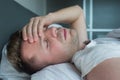 Man lying in bed at home suffering from headache or hangover