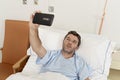 Man lying on bed hospital clinic holding mobile phone taking self portrait selfie photo sad depressed