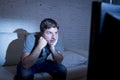 Man lying on couch at living room watching tv holding remote control looking mesmerized Royalty Free Stock Photo