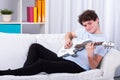 Man lying on a couch and playing guitar Royalty Free Stock Photo