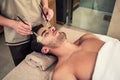 Man lying down during traditional facial treatment at beauty center