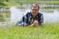 Man lying in grass on bank of pond Royalty Free Stock Photo