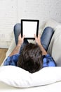 Man lying on home couch using digital tablet pad in portable internet technology Royalty Free Stock Photo