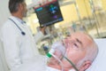 Man lying in hospital bed getting oxygen in intensive-care-unit