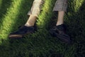 Man lying and relaxing on the grass. Legs, top view. Pair of male legs in shoes lying on green grass. Very fashionable shoes.