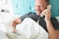 Man lying in white bed and calling on phone in hotel Royalty Free Stock Photo