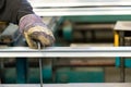 Machine operator using safety gloves controlling the stretch of an aluminiun profile with a squad Royalty Free Stock Photo