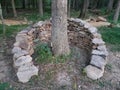 A man-mad stone wall structure surrounds a tree in a wooded area in West Virginia USA.