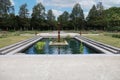 A man made pond with water plants and a sculpture at Boerner Botanical Gardens with a rose garden