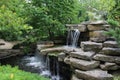 A man made stone waterfall cascading into a pond in a landscaped garden in Wisconsin Royalty Free Stock Photo