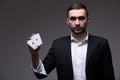 Man magician with two playing cards in his hand over grey background Royalty Free Stock Photo