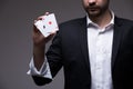 Man magician with two playing cards in his hand over grey background Royalty Free Stock Photo