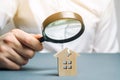 A man with a magnifying glass looks at a house with a crack. Damage assessment home and insurance risks