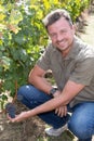 A man maintaining his vineyard smiling at camera in the grape fields