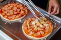 Man make pizza for donate at charity event with pizza crust and pineapple. Female chef preparing pizza with hands putting Royalty Free Stock Photo