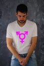 A man with make up in t-shirt with third gender symbol- transgender.