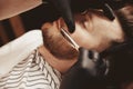 Man makes beard haircut in retro barbershop with straight razor