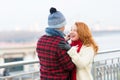 Man makes funny ginger woman in red scurf. Guy cares about woman. Woman happy to meet man in city.