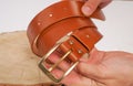 Man makes by hands leather belt with buckle. handmade hobby. young man resting by manufacture his designer belts. man with a screw