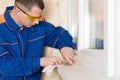 A man makes sealing of cracks of plastic windows with the help of white selicon