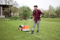 man makes a short break while cutting grass with a lawn mower after at backyard of his house. Gardening, sweating or Royalty Free Stock Photo