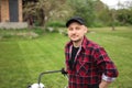 man makes a short break while cutting grass with a lawn mower after at backyard of his house. Gardening, sweating or