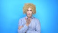 Man with makeup and a wig on a blue background sends a kiss Royalty Free Stock Photo