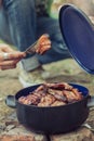 Man making barbecue and puts roasted meats in the pot