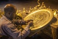 Man making the bronze tray at night