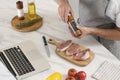 Man making dinner while watching online cooking course via laptop in kitchen, closeup Royalty Free Stock Photo