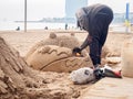 Man is making a dragon sand sculpture on the Sant Miguel beach in Barcelona Royalty Free Stock Photo