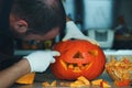 Man making Halloween pumpkin head jack lantern on wooden table at home, closeup Royalty Free Stock Photo