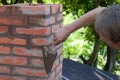 A man making masonry works, working with a trowel and making a chimney of red bricks Royalty Free Stock Photo