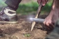 Man making a poinky wooden stick, ground view.