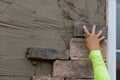 Man making texture of wall facing with decorative stone tiles bricks Royalty Free Stock Photo