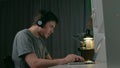 Man man in slouching position listen music on headphones use laptop at night.