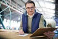 Man, manager and writing with clipboard in logistics at factory with machines for supply chain. Portrait, warehouse and Royalty Free Stock Photo
