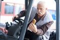 Man manoeuvering fork lift truck while holding sandwich