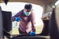 Man with mask disinfecting inside car.Prevent infection of Covid-19 virus.