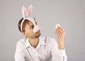 Man in the mask Easter Bunny looking at the egg Royalty Free Stock Photo