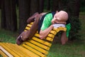 A man with a mask on a face lying on a bench backrest