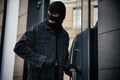 Man in mask forcing door with crow bar