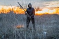 A man in a mask and goggles with a stick in his hands, post-apocalypse