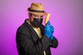 A man in a mask and a hat holds a banana in his hands like a gun Royalty Free Stock Photo