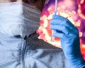 Man in a mask and protective gloves on the background of the image of a coronavirus. Doctor with a vaccine and a syringe