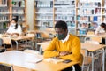 Man in mask studying in public library