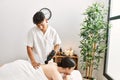 Man massaging woman back using massage gun percusion at beauty center